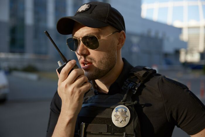 Police officer in tactical gear speaking into a walkie-talkie, representing innocent people blamed by police.