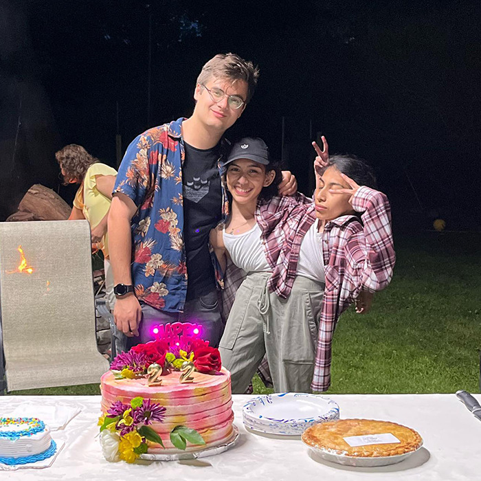 Three people celebrating outdoors at night with cakes on the table, related to conjoined twin and husband intimacy questions.