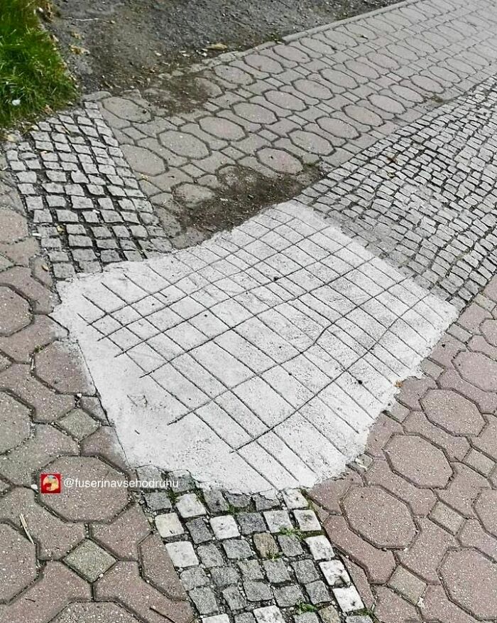 Patch of concrete poorly covering cobblestone construction with mismatched design and uneven pattern on sidewalk pavement.