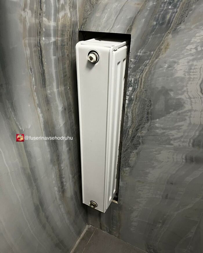 Narrow radiator awkwardly installed in a tight stone wall niche showing unusual construction and design choices.