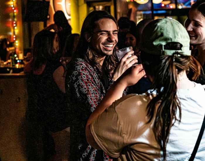 Group of adults laughing and drinking at a lively party, showing signs of not fully embracing growing up responsibilities.