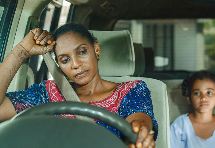 Woman looking distressed while driving with a toddler in the backseat, related to essential oils poisoning incident.