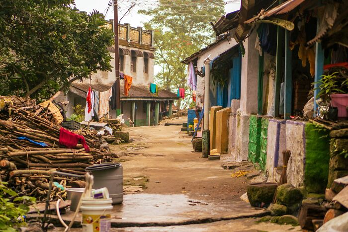 Rural village street with traditional houses and stacked firewood, illustrating stories of escape by pure luck.