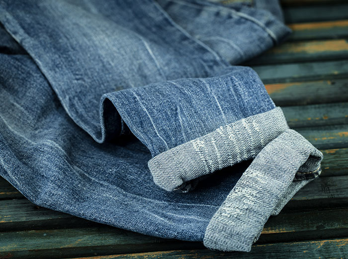 Close-up of folded denim jeans on a wooden surface representing casual style amid crazy things heard from MILs.