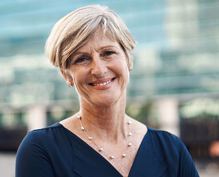 Smiling middle-aged woman outdoors, representing crazy things heard from MILs needing to calm down in family dynamics.