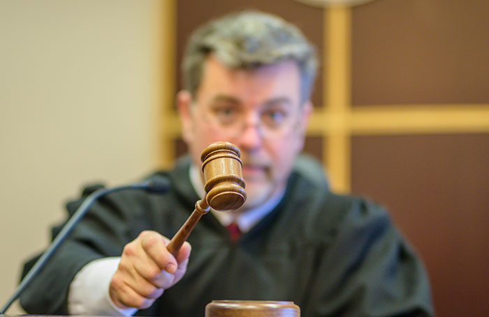 Judge in black robe holding a gavel in courtroom symbolizing authority over crazy things heard from MILs.