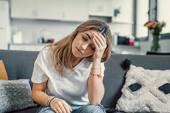 Young woman looking stressed on a couch, representing frustration from crazy things heard from MILs needing to calm down.