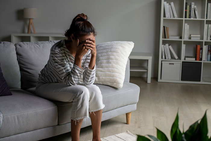 Woman sitting on couch feeling stressed and overwhelmed, representing crazy things heard from MILs that need to calm down