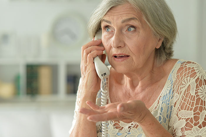 Older woman looking frustrated and speaking on phone illustrating crazy things heard from MILs that need to calm down