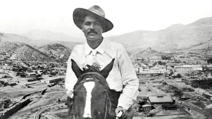 Man wearing hat on horseback overlooking a historic mining town, showcasing history anecdotes from the past.