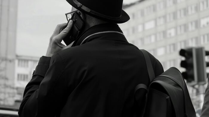 Man in a black coat and hat making a phone call on a city street, illustrating bizarre messages and phone calls.