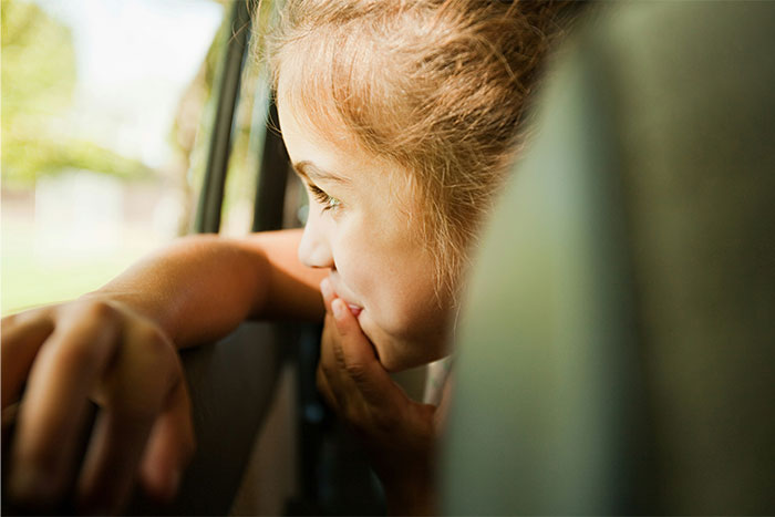 Young girl looking out car window with a curious expression, capturing people’s creepy experiences that can’t be explained.