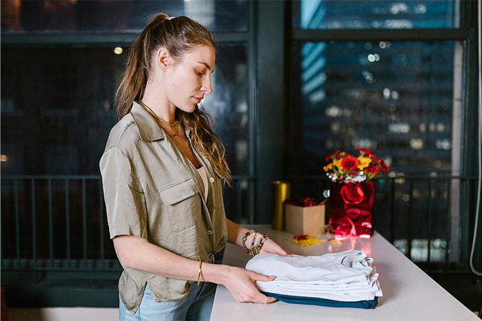 Young woman folding clothes indoors at night, reflecting on creepy things people have experienced.