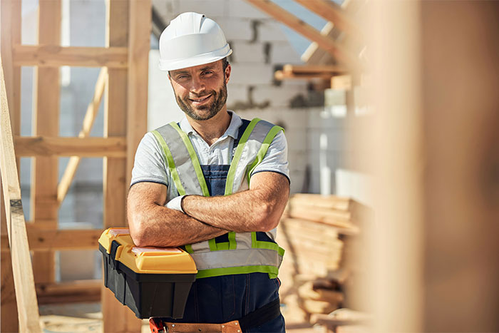 Construction worker in safety gear holding toolbox at a site, symbolizing people’s experiences with creepy unexplained things.