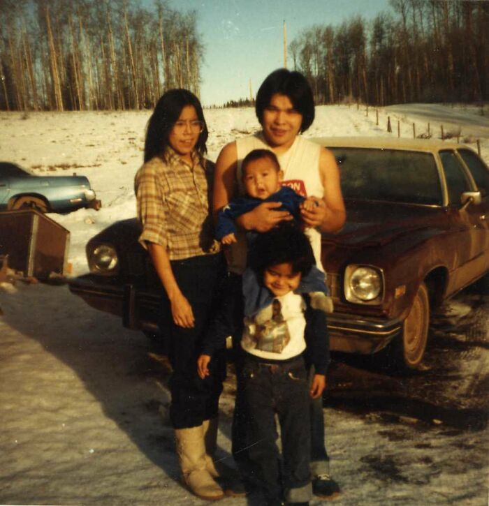 Vintage family photo with two adults and two children outdoors near a parked car, related to disappearance cases imagery.