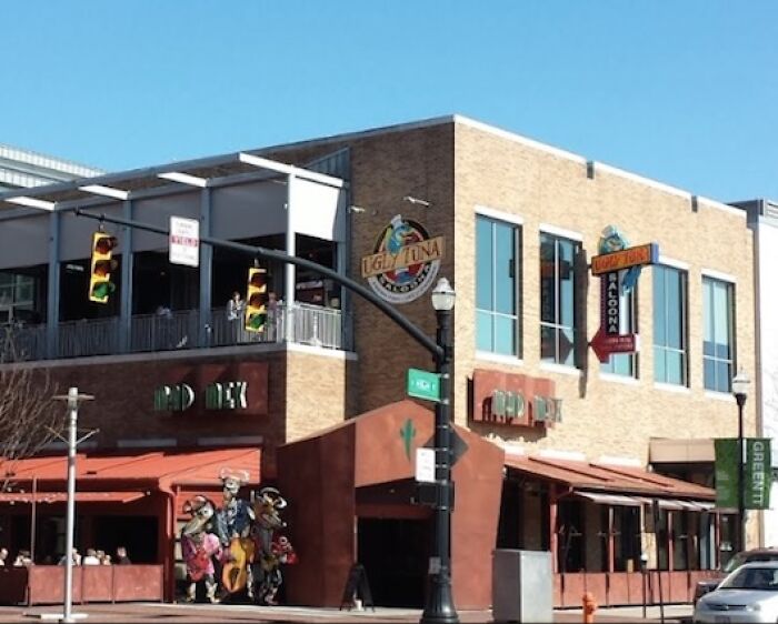 Street view of a sunny urban corner with a restaurant and traffic lights, evoking mystery from disappearance cases.