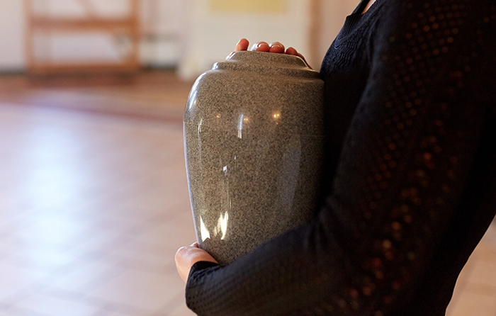 Woman holding urn with ashes indoors, expressing tension related to wife angry husband ex ashes honeymoon situation. Woman holding urn with ashes indoors, expressing tension related to wife angry husband ex ashes honeymoon situation.
