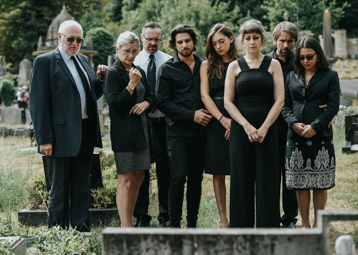 Group of people in black clothing mourning at a gravesite, reflecting on shocking family secrets uncovered.