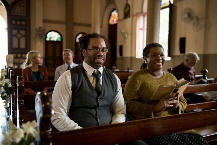 A diverse group of people sitting in a church pew, sharing real-life stories of becoming what they once hated.