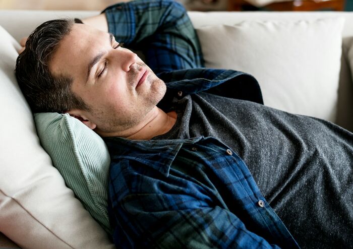 Adult man relaxing on couch with eyes closed, illustrating adults who failed to understand that growing up is mandatory.