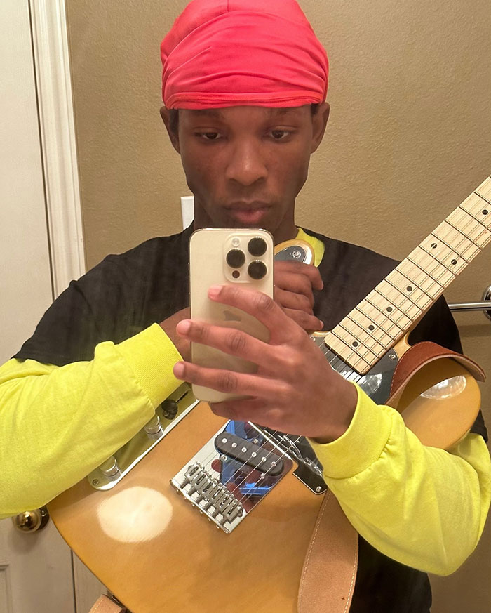 Young singer wearing red headwrap and yellow shirt takes mirror selfie holding electric guitar, hinting wild findings link to missing girl case