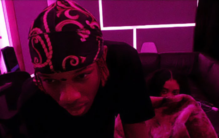 Singer D4vd in a dimly lit room with purple lighting, linked to family break silence after missing 15YO girl found.