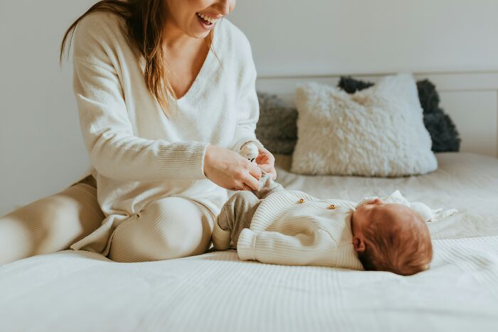 Mother in cozy outfit playing with baby on bed, illustrating relatable moments about losing savings in a single event.