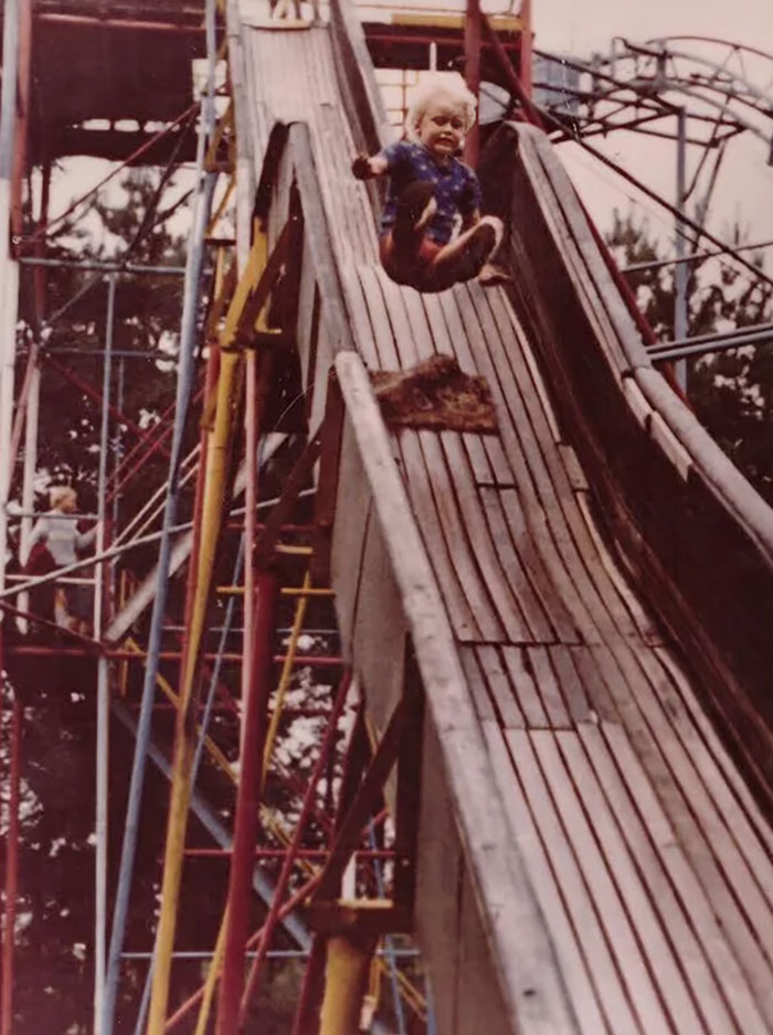 Child mid-air on a tall, historic playground slide, illustrating how being a kid back then was a life risk.