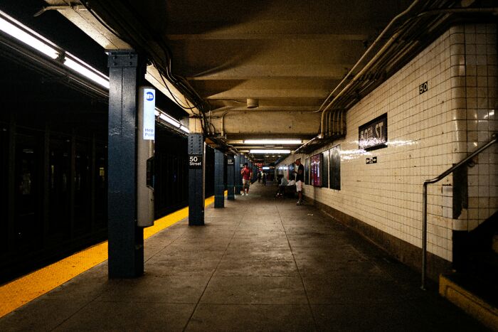 Underground subway platform with dim lighting and people waiting, illustrating people who work and explore beneath our feet.