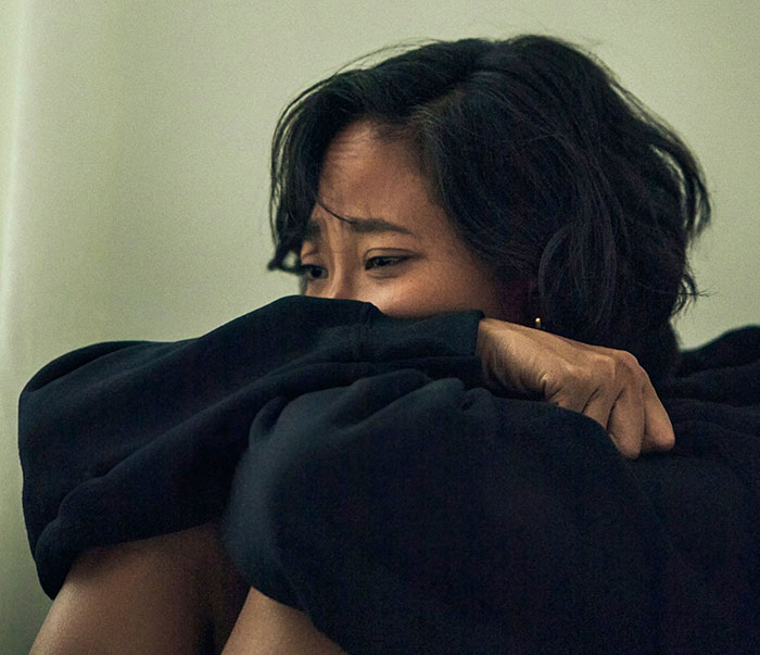 Woman sitting alone looking distressed, illustrating inlaws push boundaries during divorce conflicts.