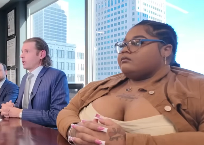 Rapper and legal team in a high-rise office discussing lawsuit settlement with Lyft after denial due to weight discrimination.