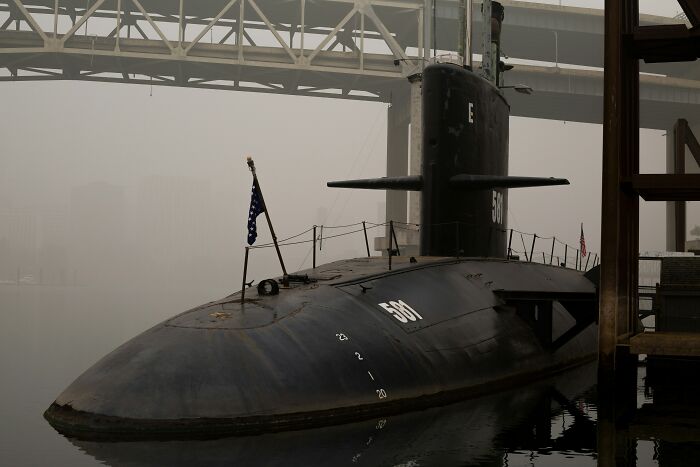 Submarine docked under a foggy bridge, representing the dark and eerie world beneath our feet explorers face.