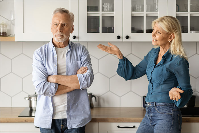 Middle-aged man and woman arguing in kitchen, illustrating conflict over defending daughter&rsquo;s room and relationship choices.
