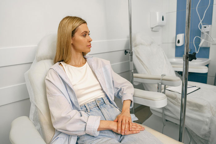 Widow sitting in a medical chair looking thoughtful, reflecting on a family dinner conflict involving her husband and sister.