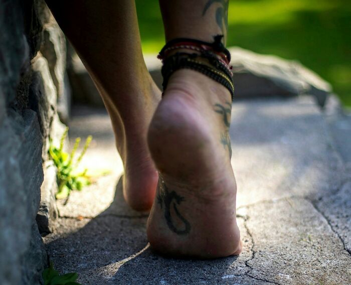 Close-up of tattooed foot with anklet bracelets outdoors, highlighting the challenges of being a tattoo artist.