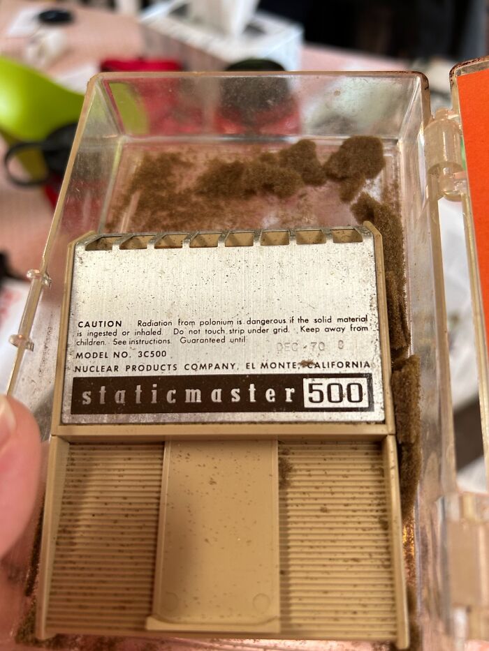 Close-up of a vintage Staticmaster 500 device warning about radiation risks from polonium exposure.