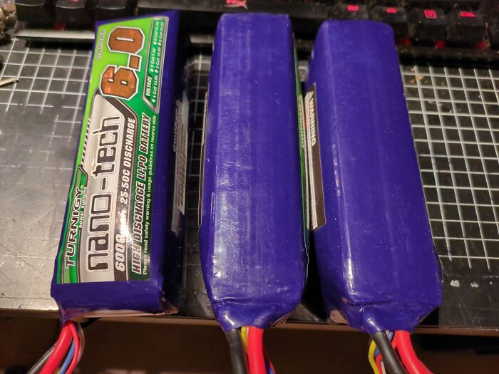 Three rechargeable LiPo battery packs on a grid cutting mat, illustrating items people mistakenly thought were edible.