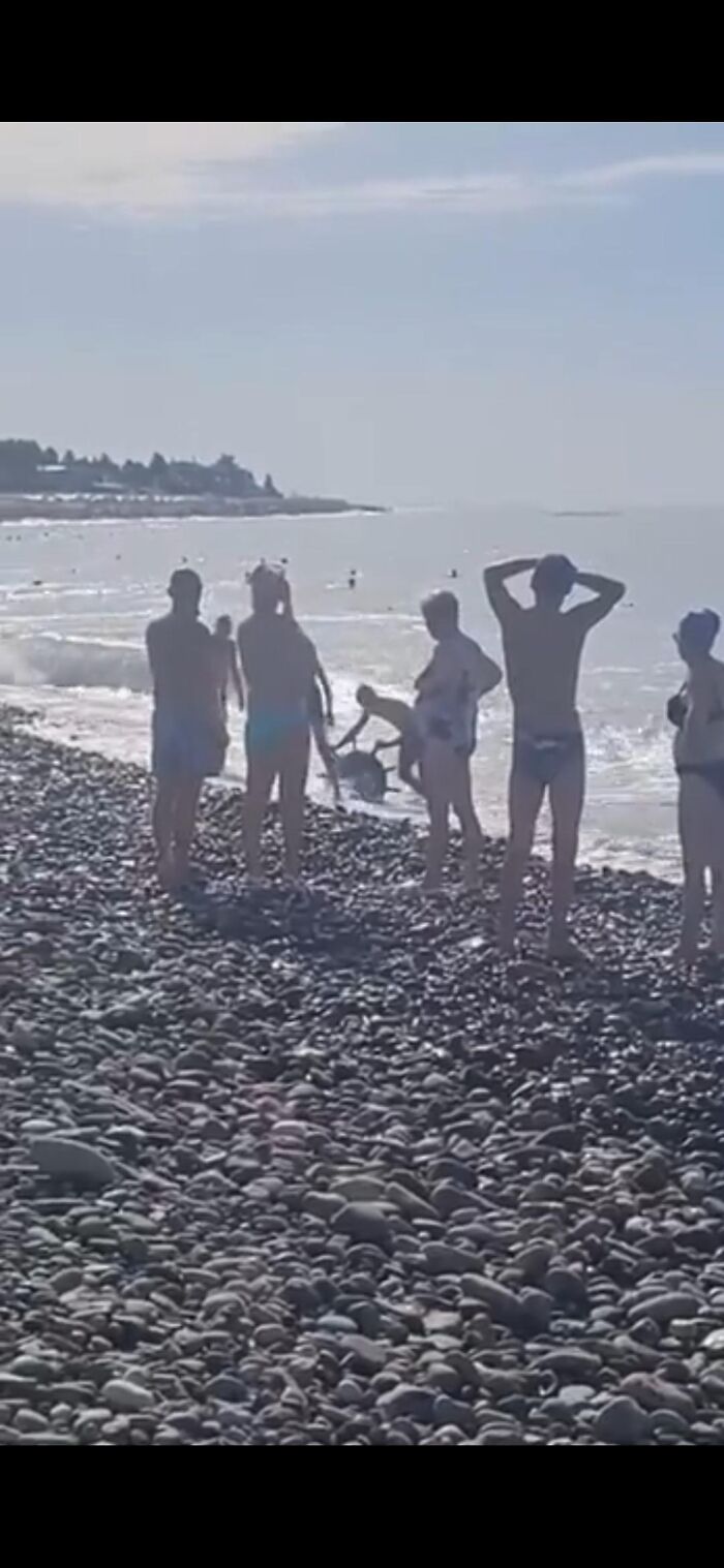 Group of people standing on a rocky beach near the water, illustrating moments from close to death experiences.