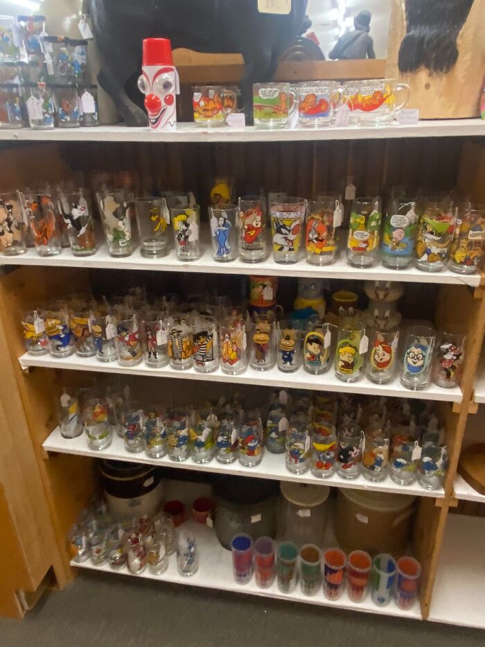 Shelf filled with colorful collectible glasses featuring cartoon characters, evoking the theme of anything is edible once.