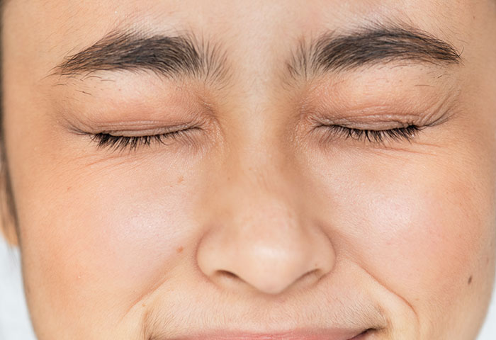 Close-up of a person grimacing with eyes shut, illustrating poor hygiene reactions that cause partners to gag.