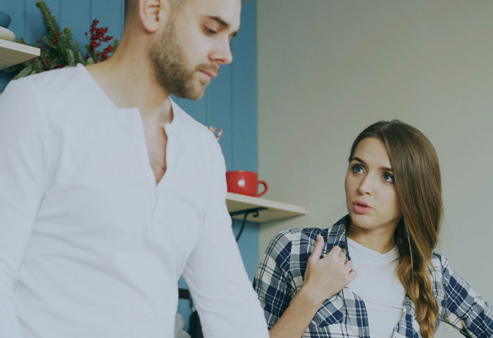 Young woman looking concerned and speaking to a man wearing white shirt, illustrating poor hygiene affecting relationships.