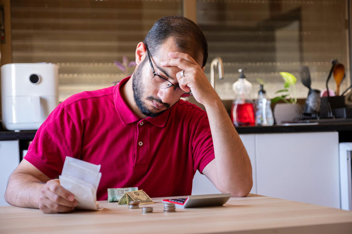 Man in red shirt stressed while counting money and bills, highlighting stepbrother financial support drama for pregnant girlfriend. Man in red shirt stressed while counting money and bills, highlighting stepbrother financial support drama for pregnant girlfriend.