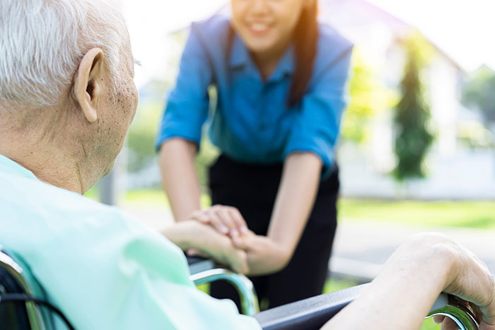 Elderly man in wheelchair holding hands with caring woman, illustrating dementia risk linked to certain food intake. Elderly man in wheelchair holding hands with caring woman, illustrating dementia risk linked to certain food intake.
