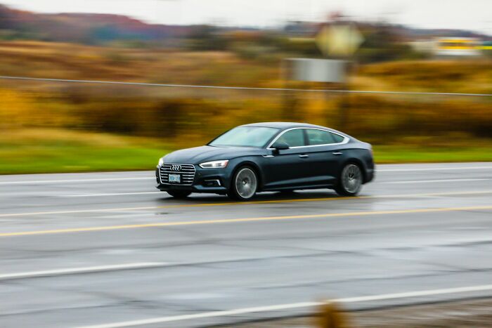 Black Audi car driving fast on wet road, illustrating unusual ways people died in almost hard to believe accidents.