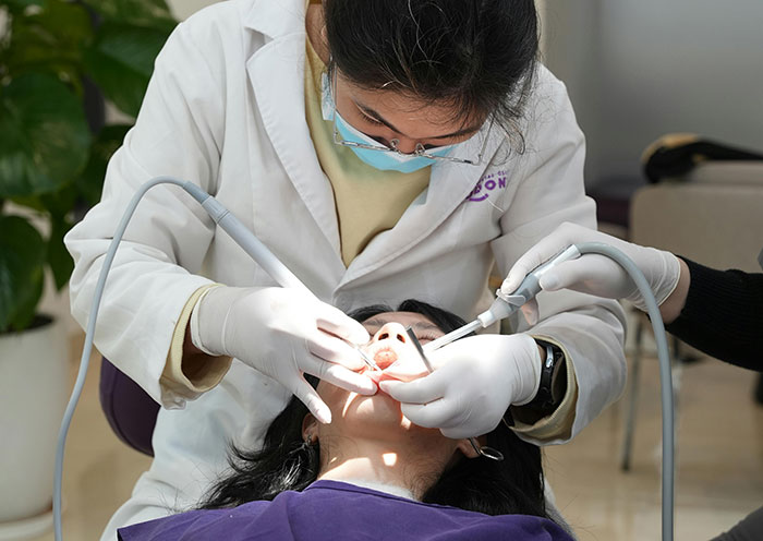 Dentist wearing gloves examining patient's teeth, monitoring dental health in a clinical setting with professional tools. Dentist wearing gloves examining patient's teeth, monitoring dental health in a clinical setting with professional tools.