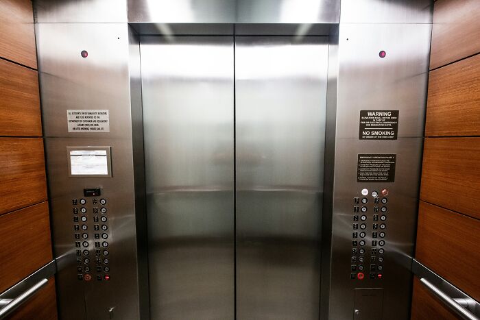 Elevator interior with stainless steel doors and wood paneling, illustrating bold decisions impacting the world.