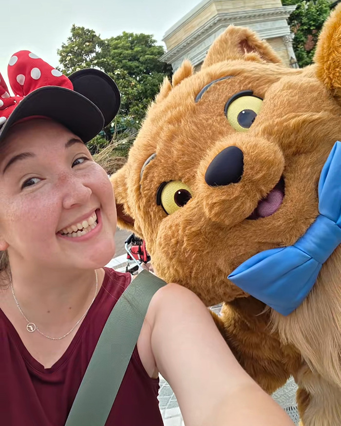 Disney influencer smiling with a theme park character before tragic accident claims children and husband in ICU.