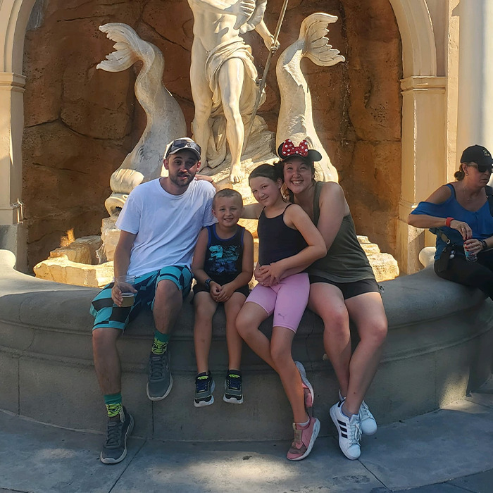 Family at a fountain with Disney-themed attire, highlighting the tragic accident claims Disney influencer's children.