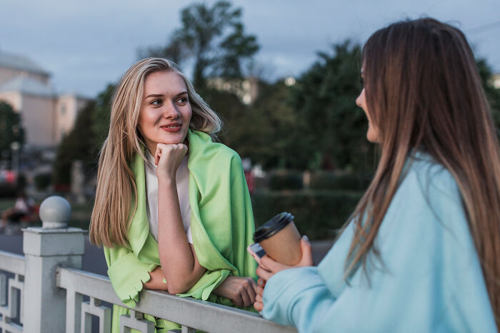 Two women outdoors, one looking thoughtful while the other holds a coffee, reflecting trust struggles after hidden affairs exposed.