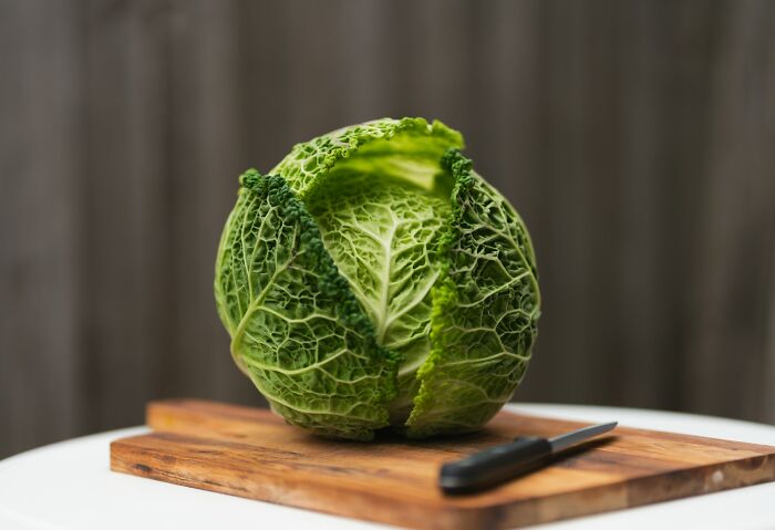Fresh green cabbage on a wooden cutting board with a knife, illustrating quick ways people have seen someone get fired.
